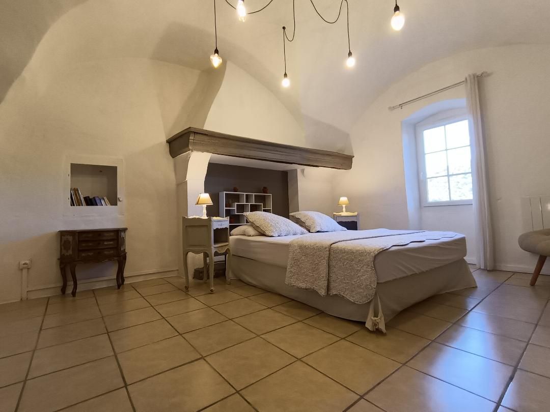 A bedroom with a large bed, bedside tables, a built-in shelf, and a window.