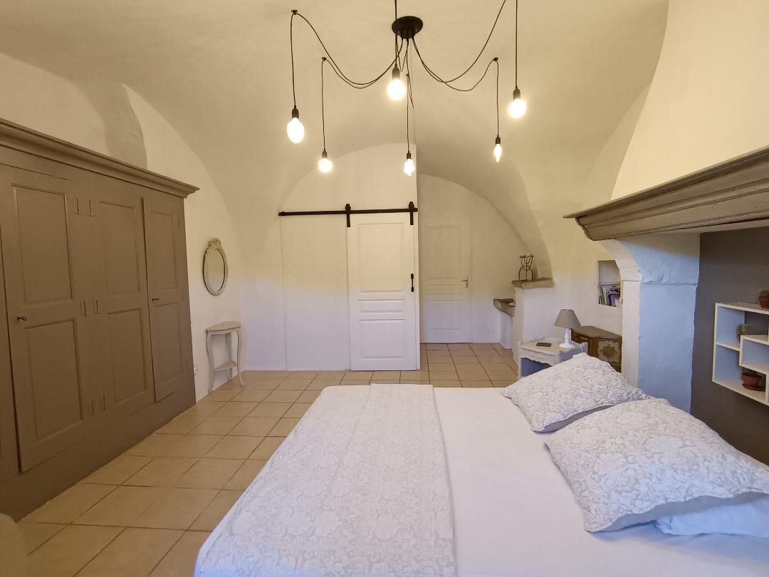 Une chambre à coucher avec un grand lit, une armoire, un miroir et un luminaire suspendu.