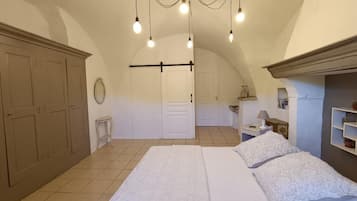 A bedroom with a large bed, a wardrobe, a mirror, and a hanging light fixture.