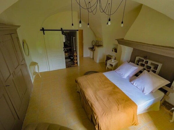 A bedroom with a bed, bedside tables, a wardrobe, and a door leading to another room.