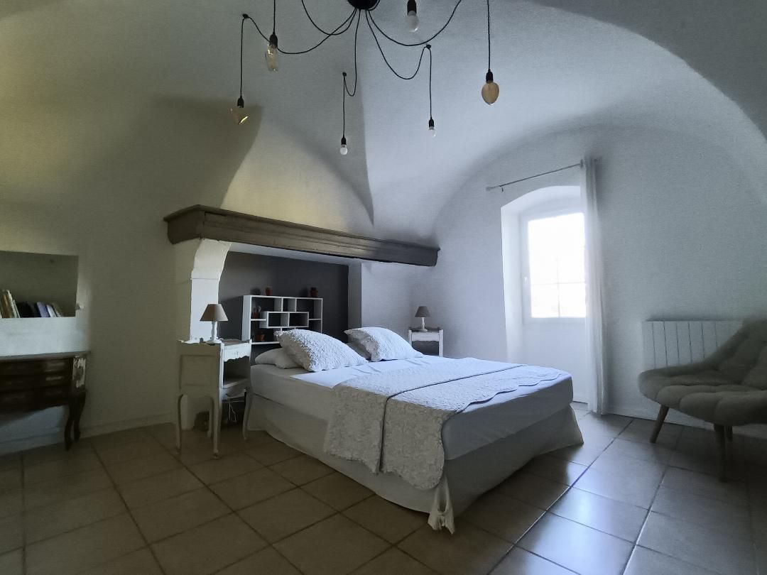 Ein Schlafzimmer mit einem Bett, Nachttischen, einem Sessel und einem Fenster.
