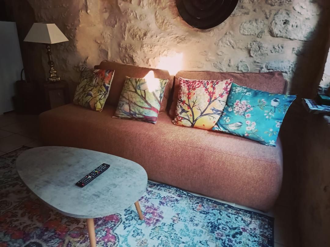 Un'accogliente zona giorno con un divano, cuscini colorati, un tavolino rotondo e una lampada.