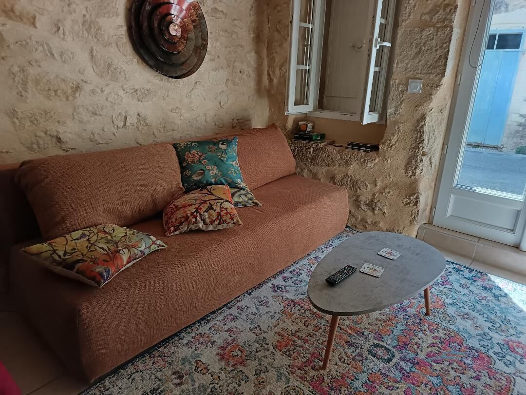 Een woonkamer met een bank, kussens, een klein tafeltje en een raam.