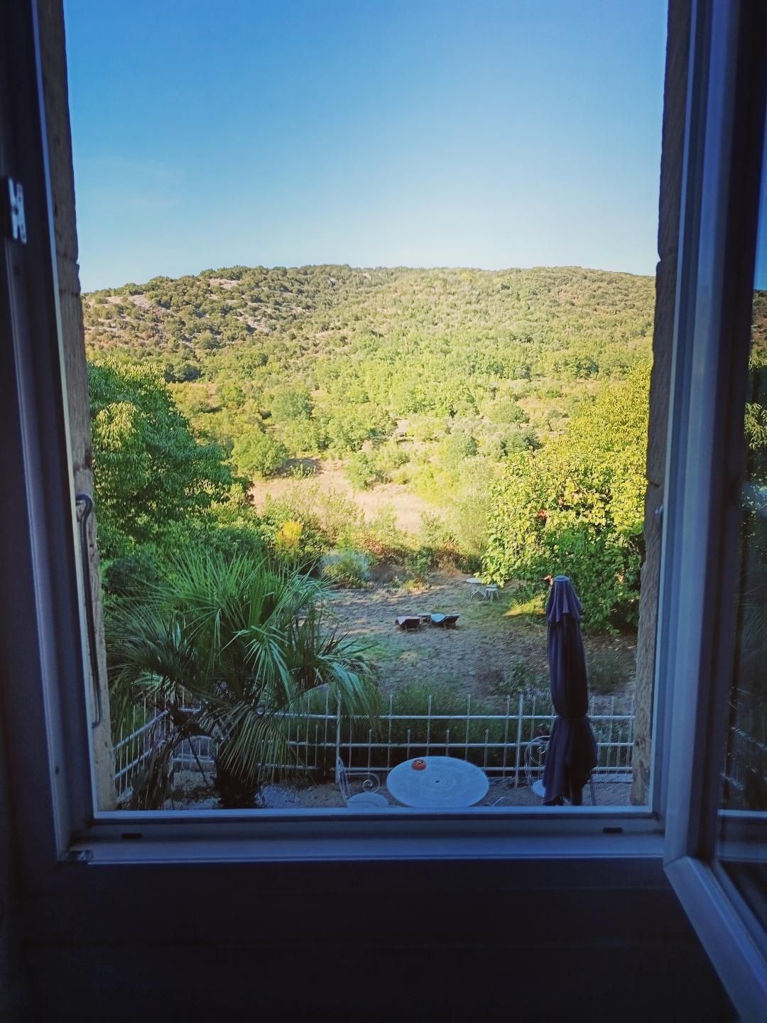 Vista dalla finestra su un giardino con recinzione, un tavolo e una sedia.