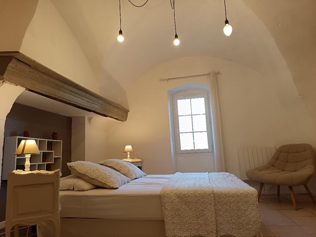 Une chambre à coucher avec un lit, des lampes de chevet, une chaise, une fenêtre et un radiateur.
