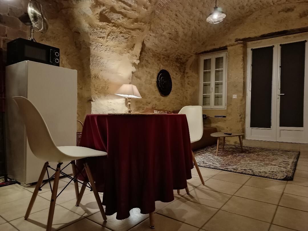 Un coin repas avec une table dressée pour deux personnes, un four à micro-ondes et une lampe fixée au mur.