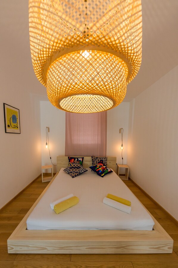 Ein modernes Schlafzimmer mit einem großen Bett, zwei Nachttischen, einer hängenden Leuchte und einer Wandlampe.