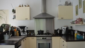 Een kleine keuken met een roestvrijstalen afzuigkap, een inbouwoven en een koffiezetapparaat op het aanrecht.