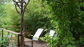 Een houten terras met twee witte stoelen en een metalen leuning.