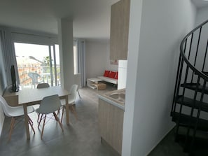 A modern apartment with a dining area, kitchen, and a staircase.