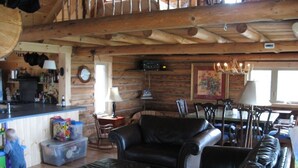 L’intérieur d’un chalet rustique, avec un plafond en bois, des canapés en cuir, un coin repas et une cuisine dotée de meubles en bois.