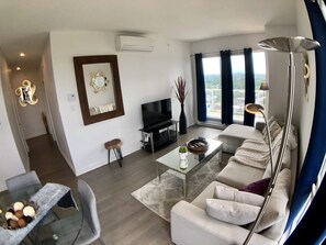 A modern living room with a sofa, TV, and a dining area with a glass table. - Stunning PENTHOUSE Top Floor 2 Bedrooms with breath taking view over Montreal / Laval (Ahuntsic CartierVille)