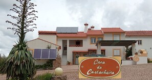 A house with a solar panel roof, a sign reading "Casa do Castanheiro", and a large plant in the foreground. - Casa do Castanheiro - Eira old farmhouse in Marvão - Portalegre - Alentejo (Marvão)