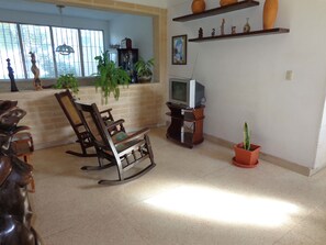 Relax in this traditional living room with a rocking chair, TV, and lush greenery.