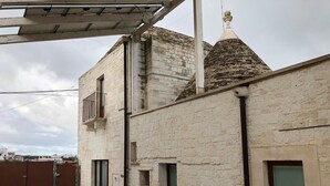 A building with a stone facade, a metal roof, and a small balcony. - Trullo Il Cantastorie (Alberobello)
