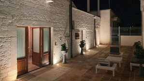 A stone building with a covered patio, outdoor seating, and a gated entrance. - Trullo Il Cantastorie (Alberobello)