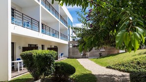 A modern building with a covered outdoor seating area, a gravel path, and well-maintained greenery. - Accès piscine ! Studio cosy et au calme ! (La Rochelle)
