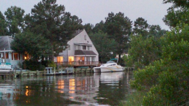 Ein Haus mit Anlegesteg und Boot, umgeben von Bäumen und Wasser.