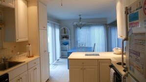 Eine Küche mit weißen Schränken, einem Deckenventilator und einem Essbereich mit Tisch und Stühlen.