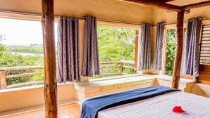 A bedroom with a wooden bed, a window seat, and curtains.