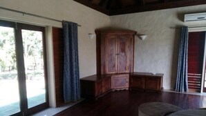 A room with a wooden cabinet, a bench, and a large window with curtains.