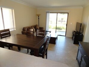 Relax in this inviting living area with a large dining table, comfortable sofa, and sliding glass door to an outdoor space.