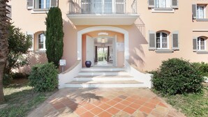 A building entrance with a reception area, a tiled pathway, and surrounding greenery. - Super endroit ! Joli Studio équipé près du Port (Grimaud)