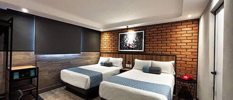 Una habitación de hotel moderna con dos camas, una pared de acento de ladrillo, un televisor montado y una pequeña mesa con un objeto rojo.