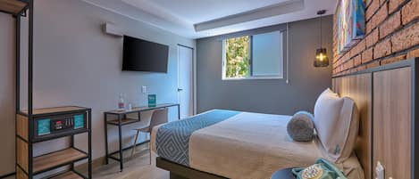 A modern hotel room with a bed, desk, chair, and a mounted television.