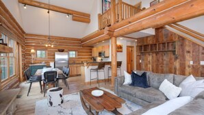 A log cabin interior with a dining area, kitchen, and living room. - Red Cloud 4 | Ski-in/Out Cabin, Hot Tub, Sleeps 12 (Big Sky)