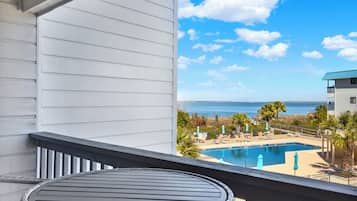 A balcony with a view of a swimming pool and the ocean.