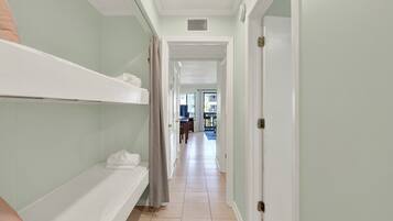 A hallway with a bunk bed, a door, and a view into another room.