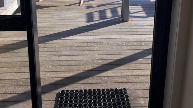 Een houten terras met een bankje en uitzicht op een weelderige tuin en heuvels.