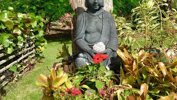 A Buddha statue in a garden with lush greenery and a clear blue sky. - STAY LOVE PLAY at Fusion Beach Villas GARDEN studio, 1/2 mi west of Jobos Beach (Bo. Bajuras, Jobos, Isabela)