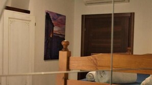 A bedroom with a wooden bed, a white door, and a painting on the wall. - L'Antica Torre Caralis Holiday (Cagliari)