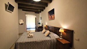 A bedroom with a bed, bedside table, lamp, and a picture on the wall. - L'Antica Torre Caralis Holiday (Cagliari)
