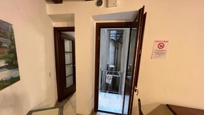A hallway with a glass door leading to a room, a painting on the wall, and a no-smoking sign. - L'Antica Torre Caralis Holiday (Cagliari)