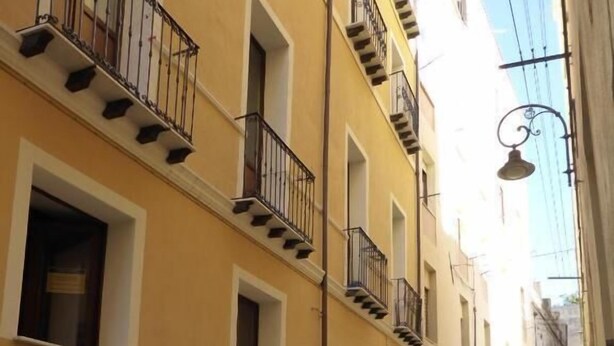 A narrow street with yellow buildings, balconies, and a tiled walkway. - L'Antica Torre Caralis Holiday (Cagliari)