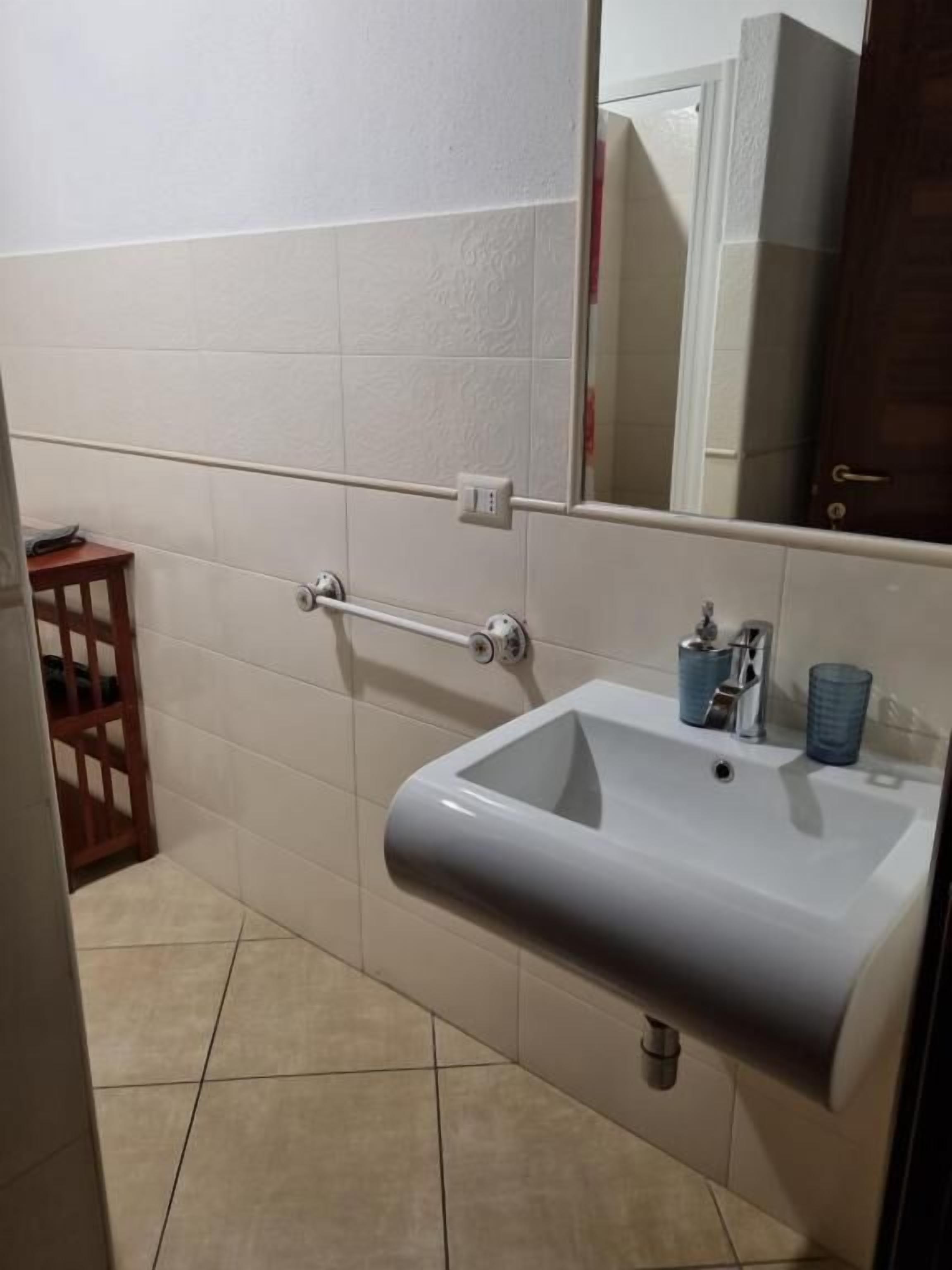 A bathroom with a sink, mirror, and towel rack.