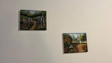 Two small paintings of gardens on a plain wall.