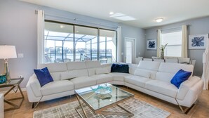 Ein modernes Wohnzimmer mit einem Ecksofa, einem Glastisch und großen Fenstern mit Blick auf die Stadt.