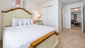 Ein ordentlich eingerichtetes Schlafzimmer mit einem großen Bett, Nachttischen, einem Kleiderschrank und einer offenen Tür zu einem Badezimmer.