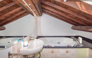 A bathroom with a white sink, a bathtub, and a shower. The ceiling is made of wooden beams. - Nice apartment in Rapallo with outdoor swimming pool (Rapallo)