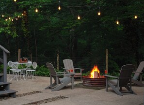 An outdoor seating area with Adirondack chairs, a fire pit, and string lights. - River's Edge on 30 Acres with Kayaks/Pool/Farm/River/Trails/Pets, near Beach (Union Pier)