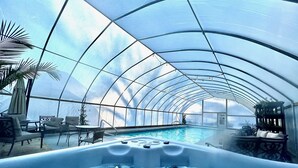 A large indoor swimming pool with a glass ceiling, surrounded by lounge chairs and a hot tub. - River's Edge on 30 Acres with Kayaks/Pool/Farm/River/Trails/Pets, near Beach (Union Pier)