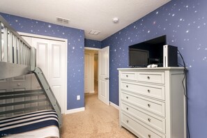 A bedroom with a starry wall design, a bunk bed, a dresser, and a television. - Storey Lake Exec Villas- 4720shd (Kissimmee)
