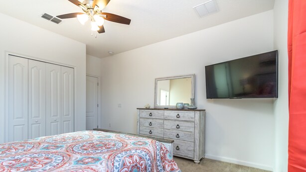 A bedroom with a bed, a dresser, a television, and a ceiling fan. - Solterra Exec Villas- 5244oa (Davenport)