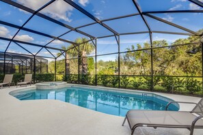 A covered outdoor swimming pool with clear blue water, surrounded by a metal frame and glass panels, with lounge chairs and a hot tub. - Solterra Exec Villas- 5244oa (Davenport)