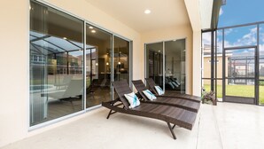 Un espace de détente extérieur moderne, doté de portes coulissantes en verre, d’un sol en béton et offrant une vue sur le quartier environnant.