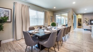 Un espace repas avec une table rectangulaire dressée pour six personnes, entourée de chaises grises.